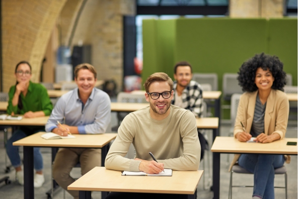 Profesionales sentados en pupitres en una charla presencial sobre disciplina positiva | Centro Logopedia | Psicólogos Online Madrid | Psicólogo de Familia | Psicólogos Madrid cerca de mi