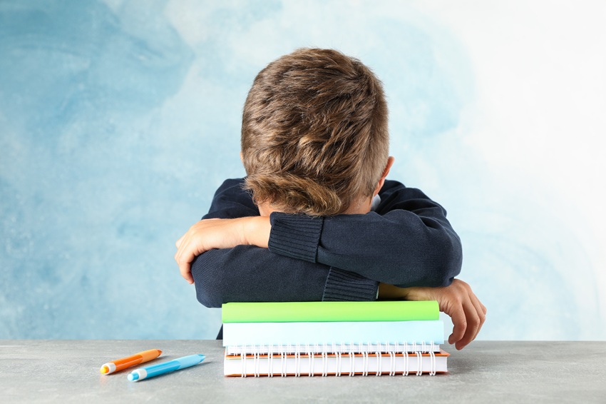 Niño apoyado en montaña de cuadernos triste | Salud Mental Infantil | Vuelta Al Cole | Terapia Infantil | Ciprea